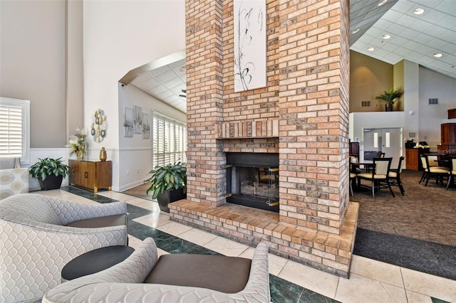 living room featuring light tile patterned flooring, a towering ceiling, and a fireplace