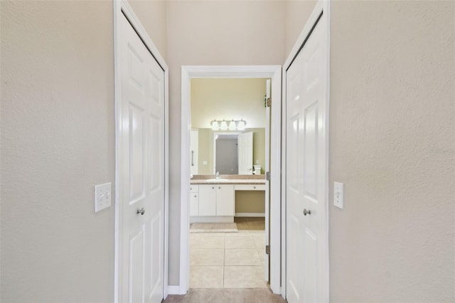 hallway with light tile patterned floors and sink