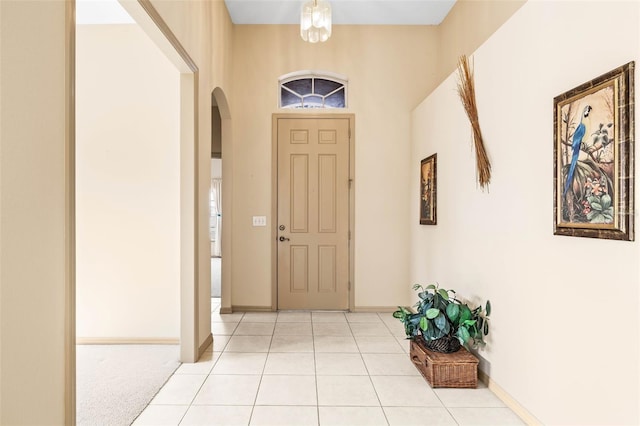 entryway featuring baseboards, arched walkways, and light tile patterned flooring