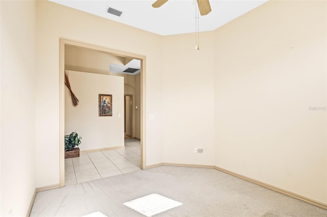 carpeted spare room with baseboards, tile patterned floors, visible vents, and a ceiling fan