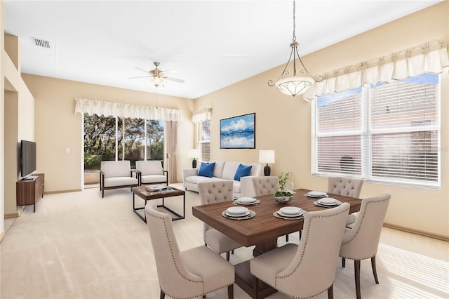 dining area with a ceiling fan, visible vents, light carpet, and baseboards