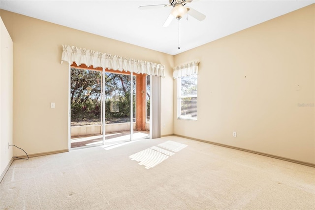 carpeted spare room with a ceiling fan and baseboards