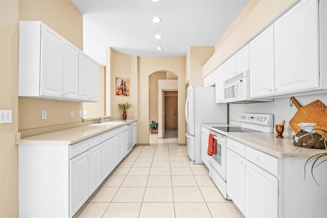 kitchen featuring arched walkways, light tile patterned floors, light countertops, white cabinetry, and white appliances