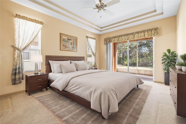 bedroom featuring light carpet, baseboards, a raised ceiling, a ceiling fan, and access to exterior