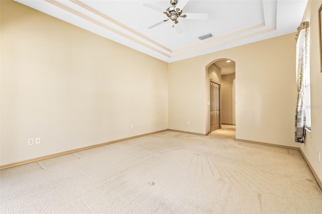 spare room with baseboards, visible vents, a raised ceiling, and arched walkways