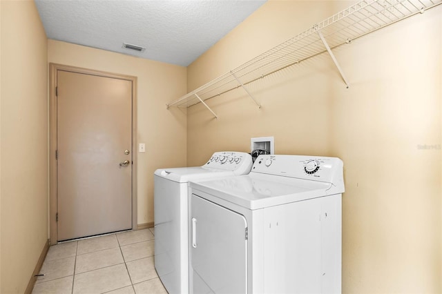 laundry room with laundry area, visible vents, independent washer and dryer, a textured ceiling, and light tile patterned flooring