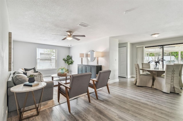 dining room featuring ceiling fan, a textured ceiling, dark wood-type flooring, and a healthy amount of sunlight