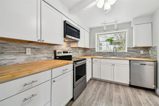 kitchen featuring stainless steel appliances, butcher block counters, sink, and white cabinets