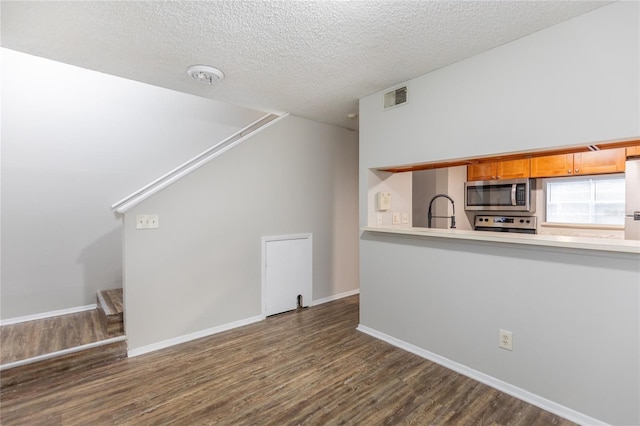 unfurnished living room with dark hardwood / wood-style floors, sink, and a textured ceiling