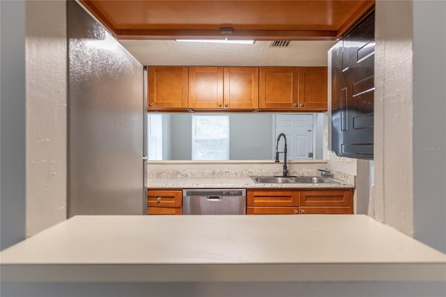 kitchen featuring stainless steel dishwasher, sink, and a textured ceiling