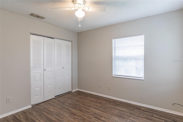 unfurnished bedroom featuring dark wood-type flooring, ceiling fan, a closet, and a textured ceiling