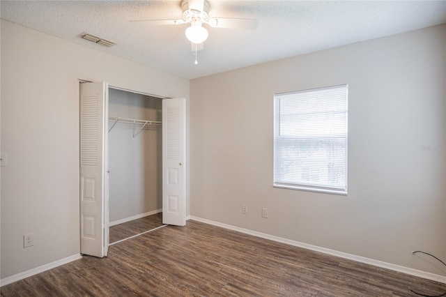 unfurnished bedroom featuring ceiling fan, dark hardwood / wood-style floors, a textured ceiling, and a closet