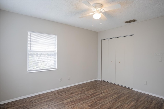 unfurnished bedroom featuring ceiling fan, dark wood-type flooring, a textured ceiling, and a closet