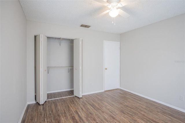 unfurnished bedroom featuring ceiling fan, dark hardwood / wood-style flooring, a closet, and a textured ceiling