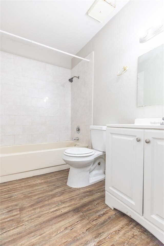 full bathroom with hardwood / wood-style flooring, vanity, toilet, and tiled shower / bath combo