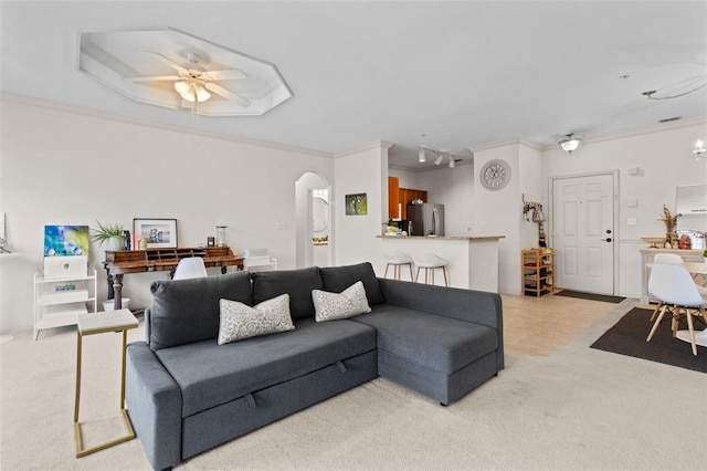 carpeted living room with arched walkways, rail lighting, crown molding, and ceiling fan