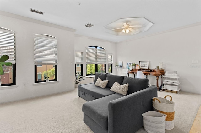 living area with ceiling fan, ornamental molding, visible vents, and light colored carpet