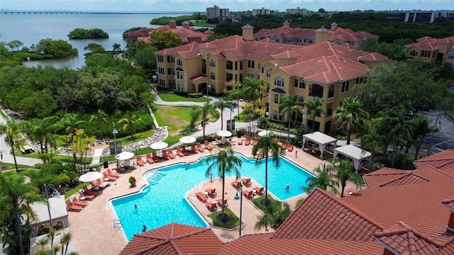 community pool with a water view, a patio area, and fence