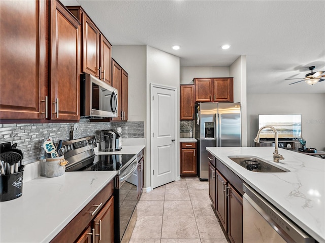 kitchen with sink, tasteful backsplash, appliances with stainless steel finishes, ceiling fan, and light stone countertops