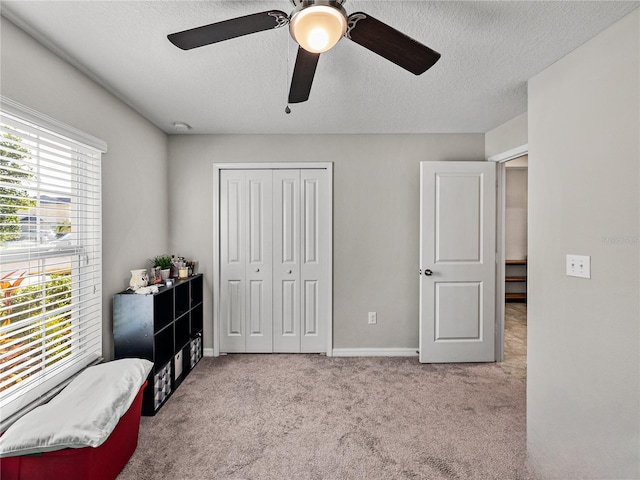 bedroom featuring ceiling fan, light colored carpet, a textured ceiling, and a closet