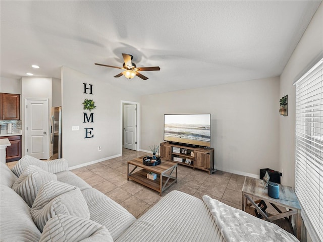 living room with light tile patterned flooring, ceiling fan, and a textured ceiling