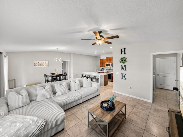 tiled living room featuring ceiling fan with notable chandelier and a textured ceiling