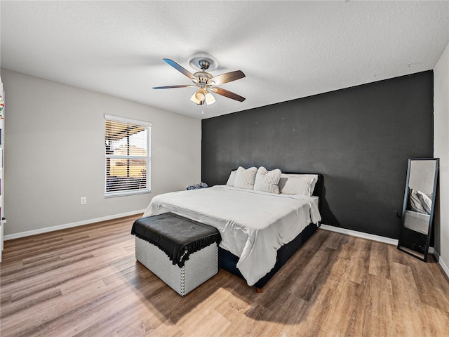 bedroom featuring hardwood / wood-style flooring, a textured ceiling, and ceiling fan