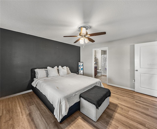 bedroom with ceiling fan, hardwood / wood-style floors, a textured ceiling, and ensuite bath