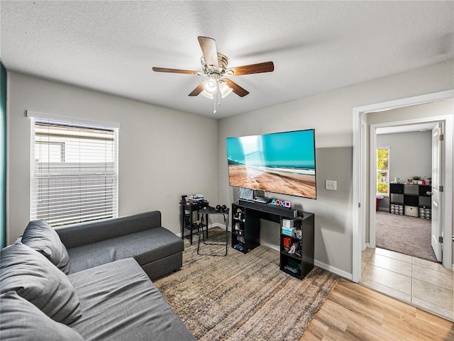 living room featuring ceiling fan, a textured ceiling, and light hardwood / wood-style floors