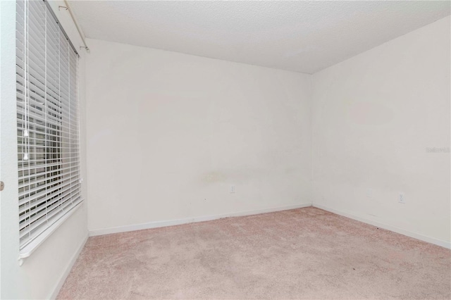 spare room featuring light carpet and a textured ceiling