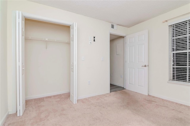 unfurnished bedroom featuring light colored carpet, a closet, and a textured ceiling