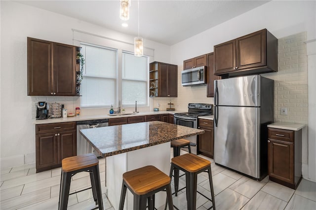 kitchen with sink, a breakfast bar area, stainless steel appliances, a center island, and decorative backsplash