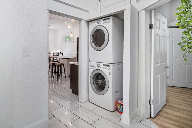 clothes washing area featuring stacked washing maching and dryer and light hardwood / wood-style flooring