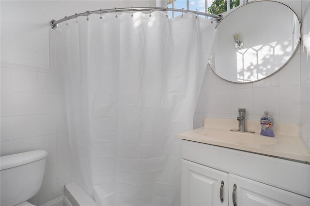 bathroom with vanity, toilet, and tile walls