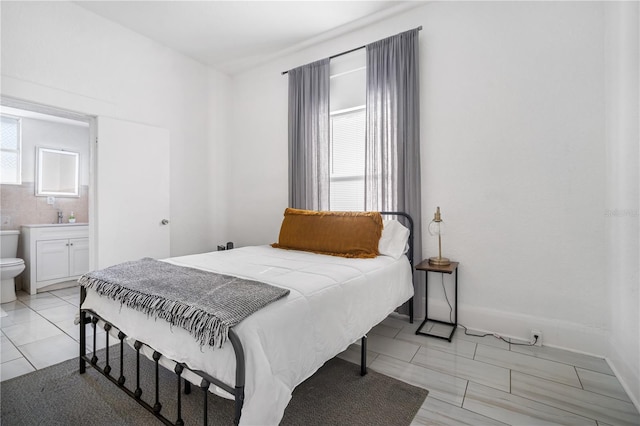 bedroom with ensuite bath, sink, and multiple windows