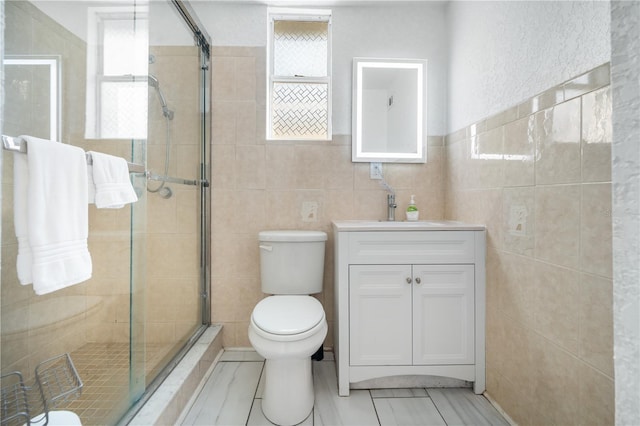 bathroom with tile walls, vanity, toilet, and walk in shower