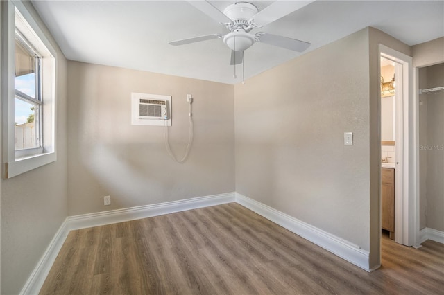 unfurnished room featuring wood-type flooring, a wall mounted air conditioner, and ceiling fan