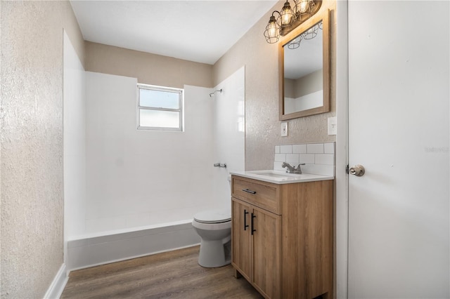 bathroom with wood-type flooring, toilet, vanity, and a tile shower