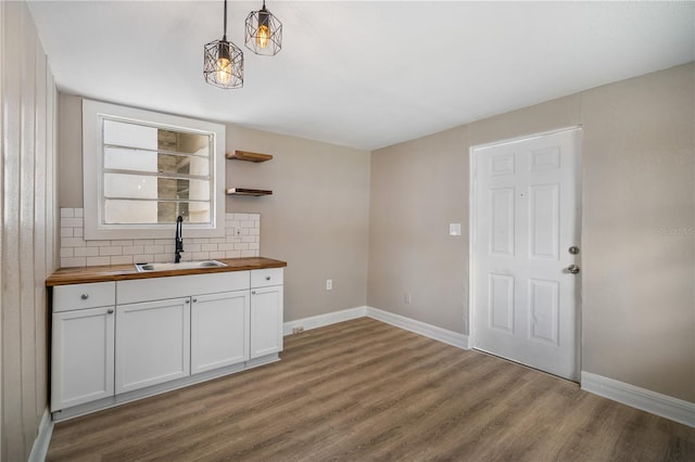 kitchen featuring sink, wooden counters, decorative light fixtures, wood-type flooring, and white cabinets