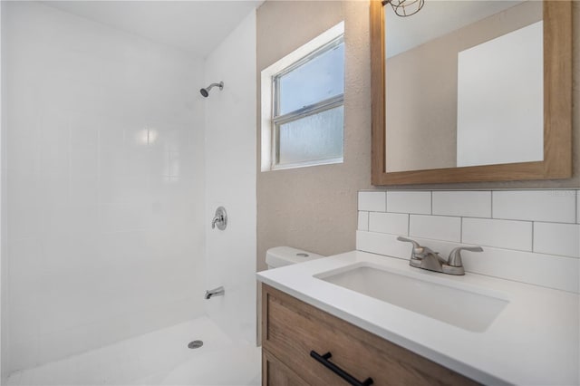 bathroom with vanity, backsplash, and tiled shower