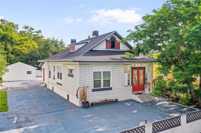 view of front of house with a garage, an outdoor structure, and a patio area