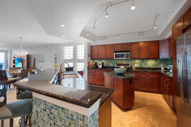 kitchen featuring a large island, sink, hanging light fixtures, stainless steel appliances, and tasteful backsplash