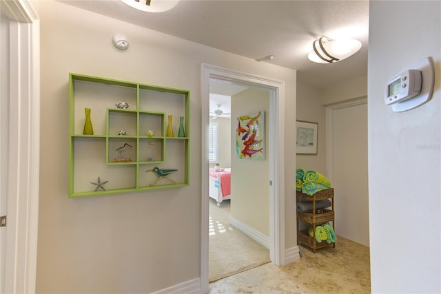 hallway featuring light colored carpet and a textured ceiling