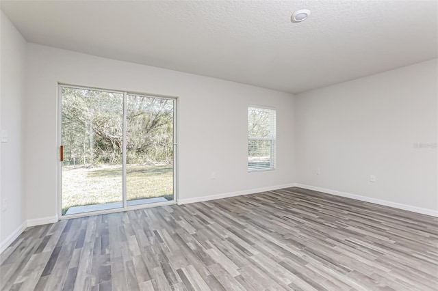 unfurnished room with a textured ceiling and light wood-type flooring