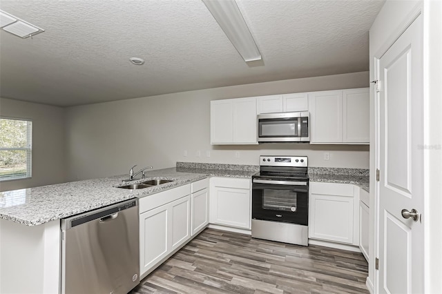 kitchen featuring white cabinetry, stainless steel appliances, kitchen peninsula, and sink