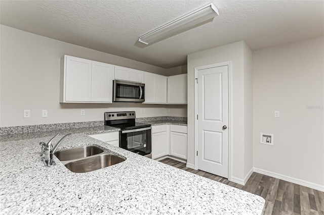 kitchen with sink, appliances with stainless steel finishes, white cabinetry, dark hardwood / wood-style floors, and light stone countertops