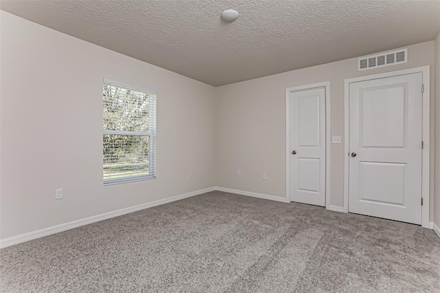 unfurnished bedroom with light colored carpet and a textured ceiling