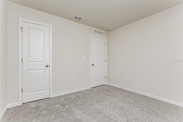 spare room with light colored carpet and a textured ceiling