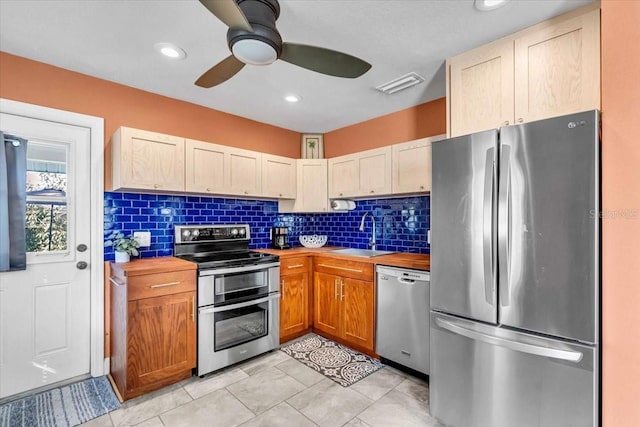 kitchen featuring sink, ceiling fan, stainless steel appliances, wood counters, and decorative backsplash