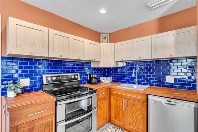 kitchen featuring tasteful backsplash, butcher block counters, appliances with stainless steel finishes, and sink